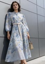 Αέρινο 3/4 φόρεμα με γαλάζιο floral print, 3/4 μανίκια και μπεζ πλεκτή ζώνη στη μέση, σε κομψή ρομαντική γραμμή.