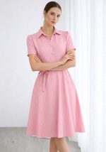 Ροζ midi φόρεμα με κάθετες ρίγες, κοντά μανίκια, χρυσά κουμπιά και υφασμάτινη ζώνη στη μέση.